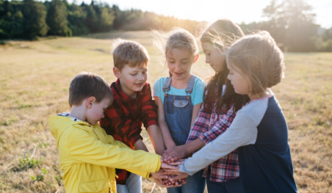 Kinderen staan in een kring met handen op elkaar 