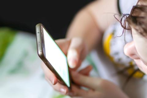 Tiener kijkt naar scherm van smartphone in closeup