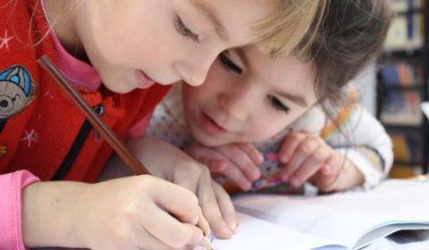 Twee kinderen schrijven samen in een boek