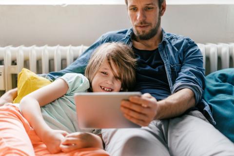 Kind en ouder kijken samen naar een tablet in de zetel