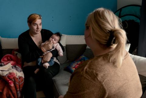 Gezinsondersteuner Melissa in gesprek met moeder die baby vasthoudt